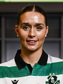 Shamrock Rovers female player in team jersey, smiling, in stadium setting.