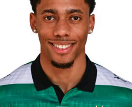 Shamrock Rovers football player in team kit, smiling, Irish club logo visible.