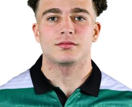 Young male football player in Shamrock Rovers jersey, close-up portrait, team logo visible, focused.
