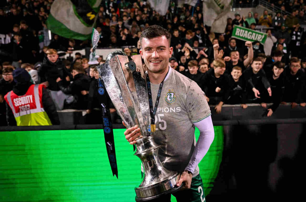 Shamrock Rovers player celebrating with trophy after winning Irish Premier Division title.
