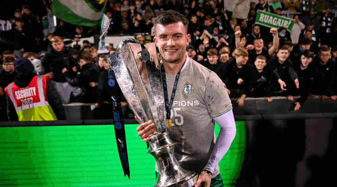 Shamrock Rovers player celebrating with trophy after winning Irish Premier Division title.