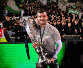 Shamrock Rovers player celebrating with trophy after winning Irish Premier Division title.