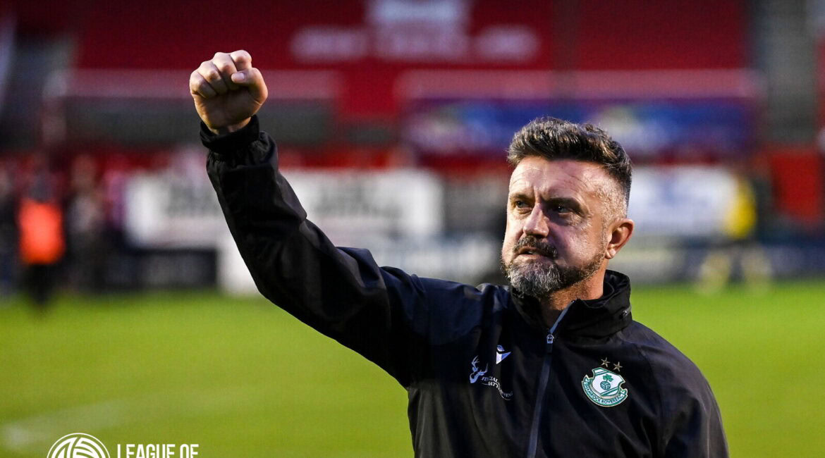 Celebrating Shamrock Rovers' victory, featuring a coach with the club badge, on a football pitch.