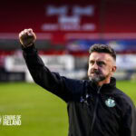 Celebrating Shamrock Rovers' victory, featuring a coach with the club badge, on a football pitch.