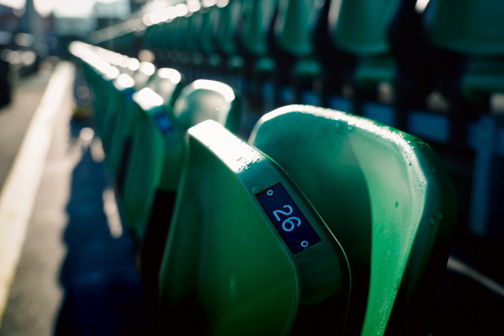 Empty green stadium seats at Tallaght Stadium, home of Shamrock Rovers, with sunlight casting shadows.