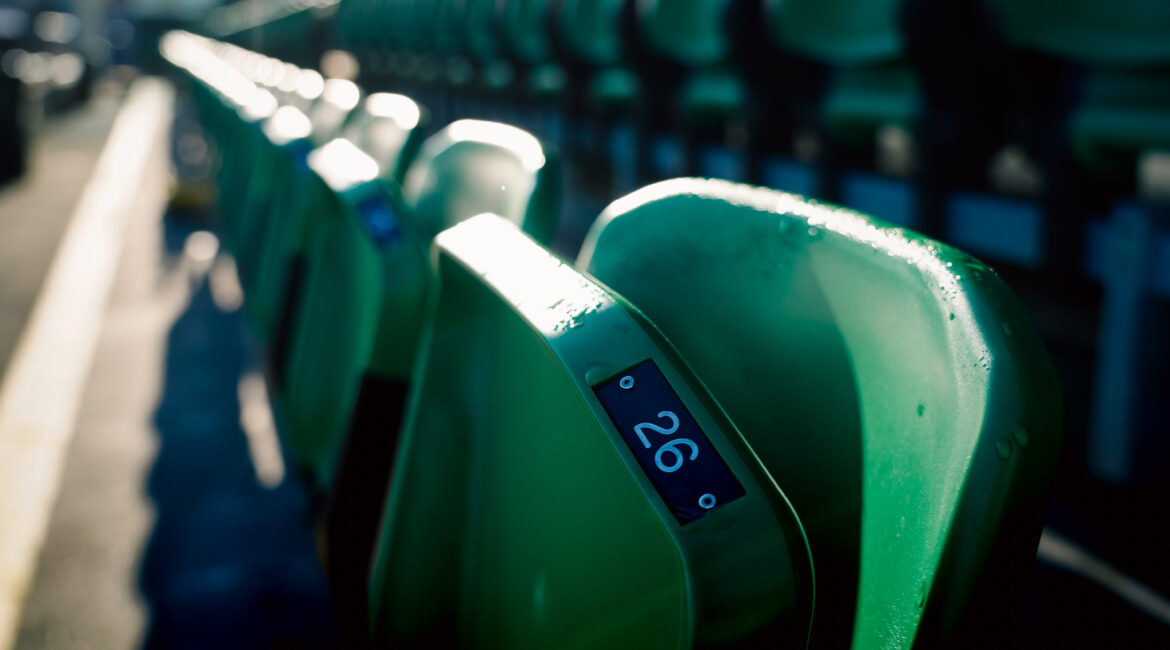 Empty green stadium seats at Tallaght Stadium, home of Shamrock Rovers, with sunlight casting shadows.