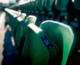 Empty green stadium seats at Tallaght Stadium, home of Shamrock Rovers, with sunlight casting shadows.