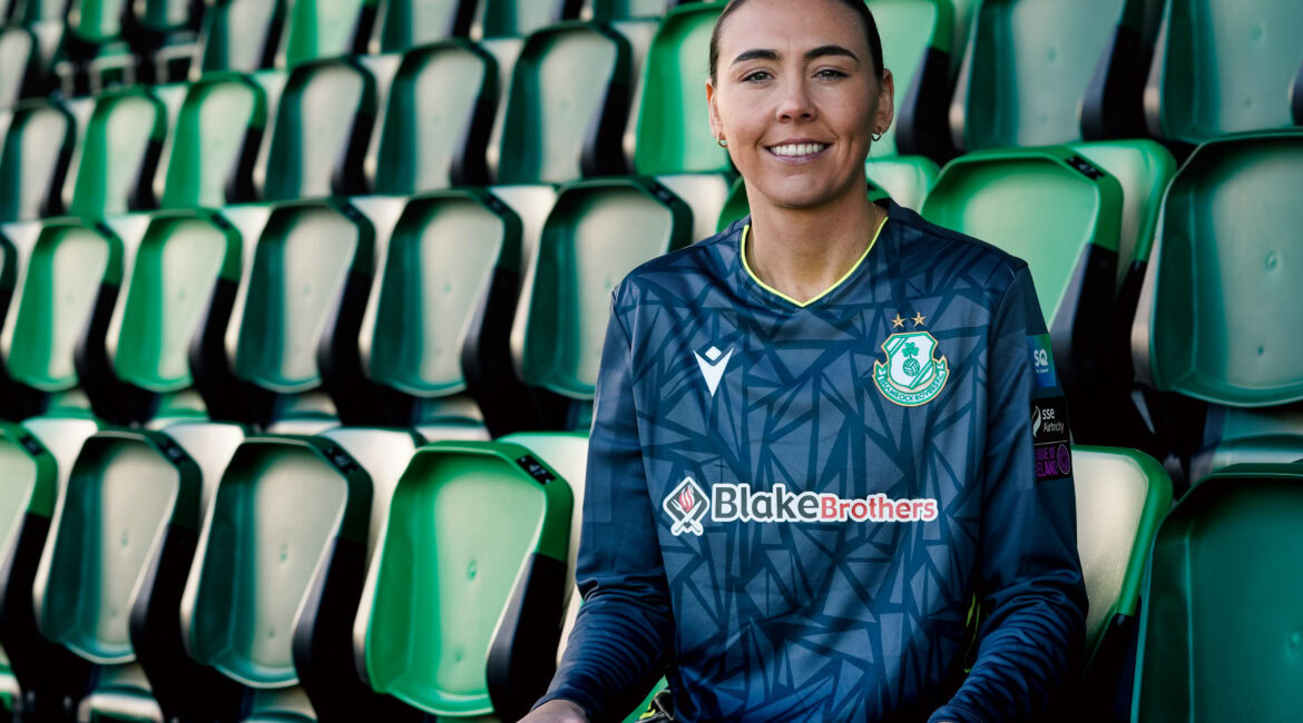 Shamrock Rovers female player smiling in team jersey at Tallaght Stadium.