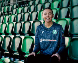 Shamrock Rovers female player smiling in team jersey at Tallaght Stadium.