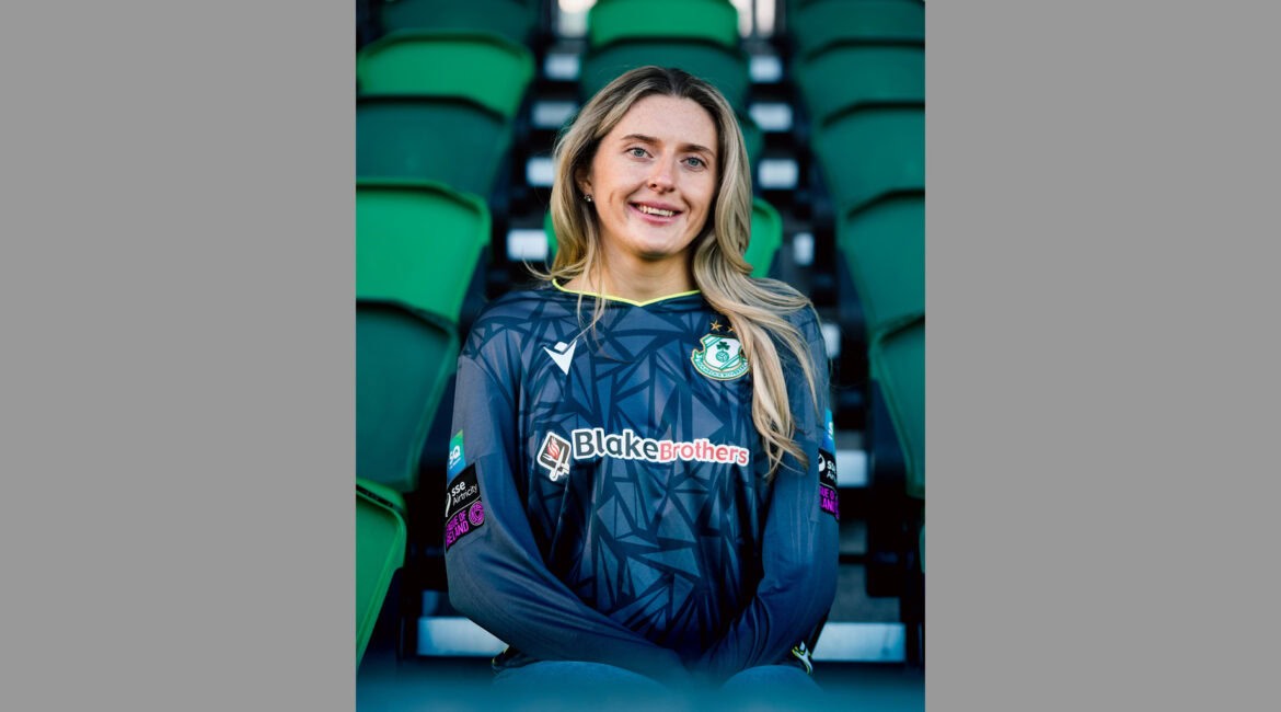 Shamrock Rovers female football player in club jersey at stadium seats.