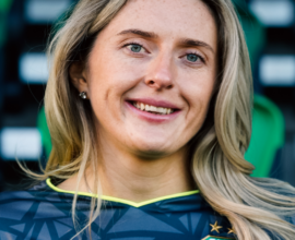 Shamrock Rovers female player in team jersey, smiling at stadium.