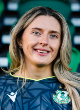 Shamrock Rovers female player in team jersey, smiling at stadium.
