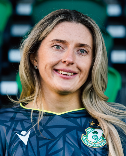Shamrock Rovers female player in team jersey, smiling at stadium.