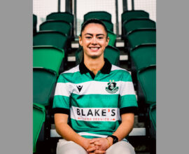 Woman wearing Shamrock Rovers football kit, smiling at stadium.