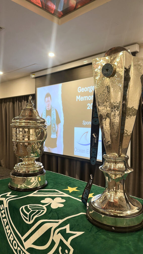 Shamrock Rovers trophy presentation at a memorial event, showcasing silver cups and medals.