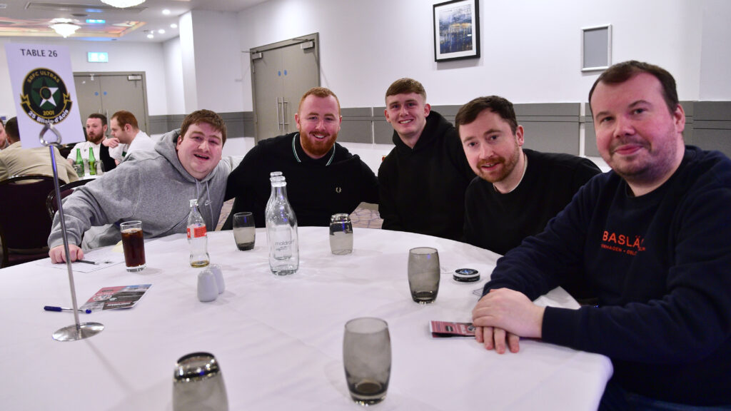 Happy Shamrock Rovers fans enjoying team night out at a social event with drinks.