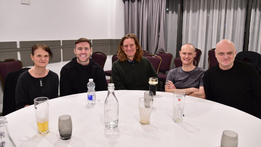 Cheerful group of people at Shamrock Rovers football club dinner or event, smiling at the camera.