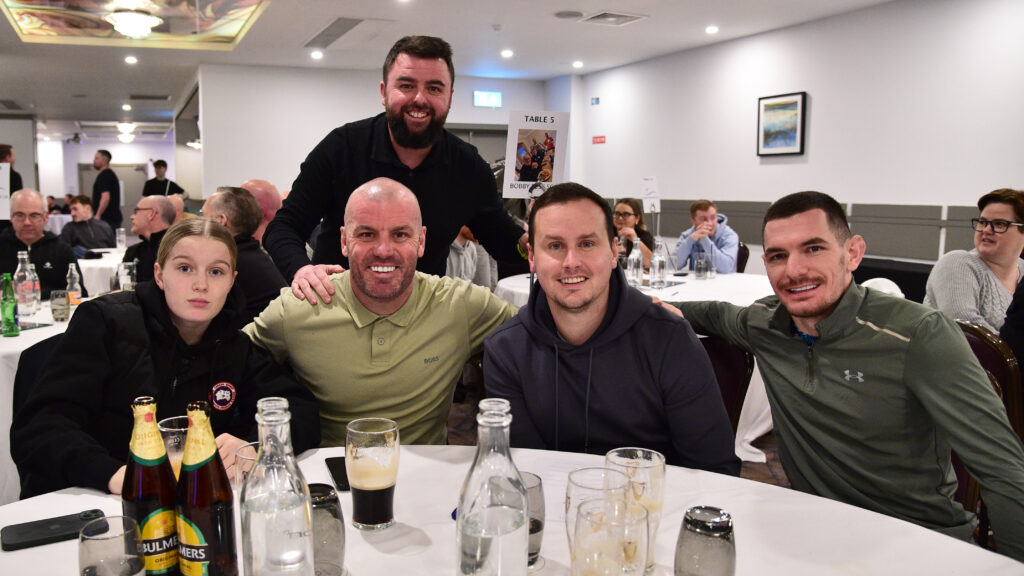 Cheerful Shamrock Rovers supporters gather for a meal at a fan event in Ireland.