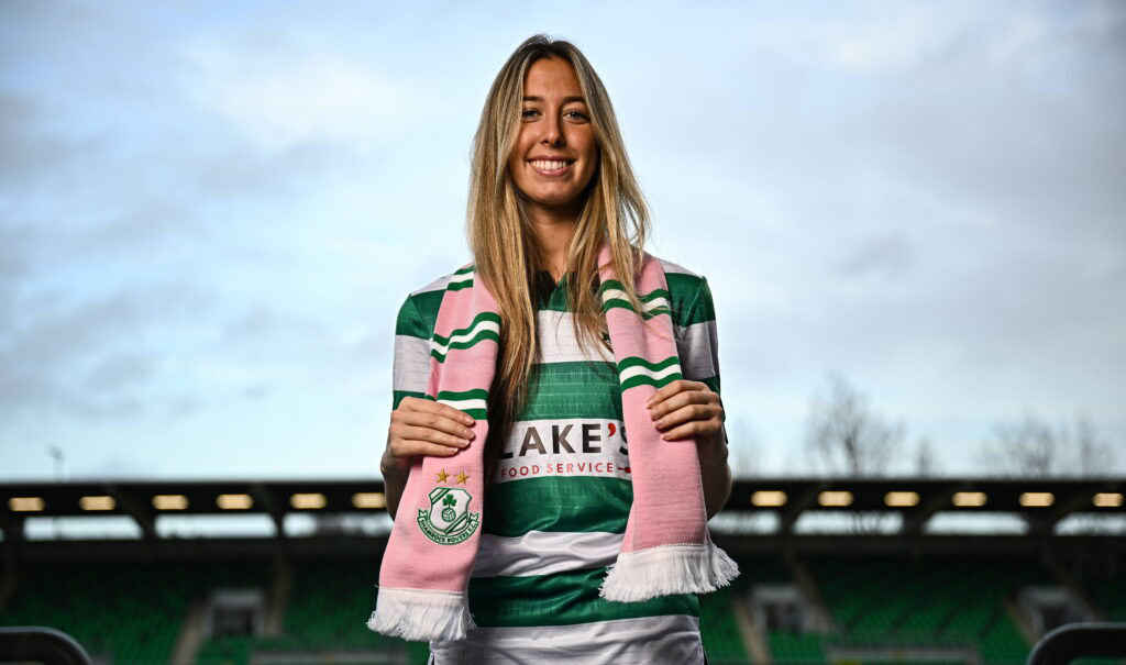 Shamrock Rovers female player smiling at Tallaght Stadium in green and white kit.