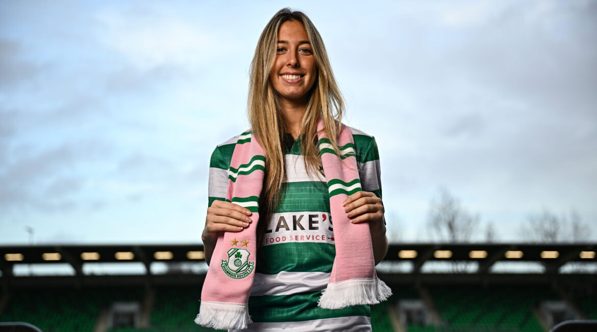 Shamrock Rovers female player smiling at Tallaght Stadium in green and white kit.