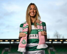 Shamrock Rovers female player smiling at Tallaght Stadium in green and white kit.