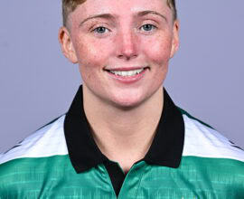 Female Shamrock Rovers player in team jersey smiling at camera.