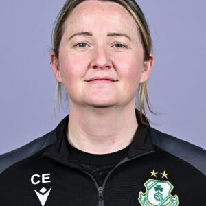 Shamrock Rovers female coach in team jacket with club crest, smiling confidently.
