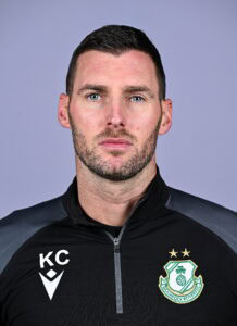 Shamrock Rovers coach in team gear, looking serious, with club crest visible on his jacket.