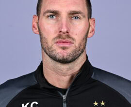 Shamrock Rovers coach in team gear, looking serious, with club crest visible on his jacket.