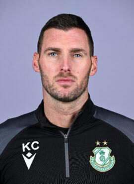 Shamrock Rovers coach in team gear, looking serious, with club crest visible on his jacket.