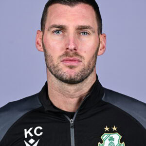 Shamrock Rovers coach in team gear, looking serious, with club crest visible on his jacket.