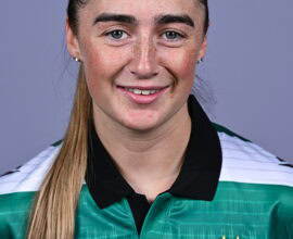 Female Shamrock Rovers player in team jersey smiling at camera.