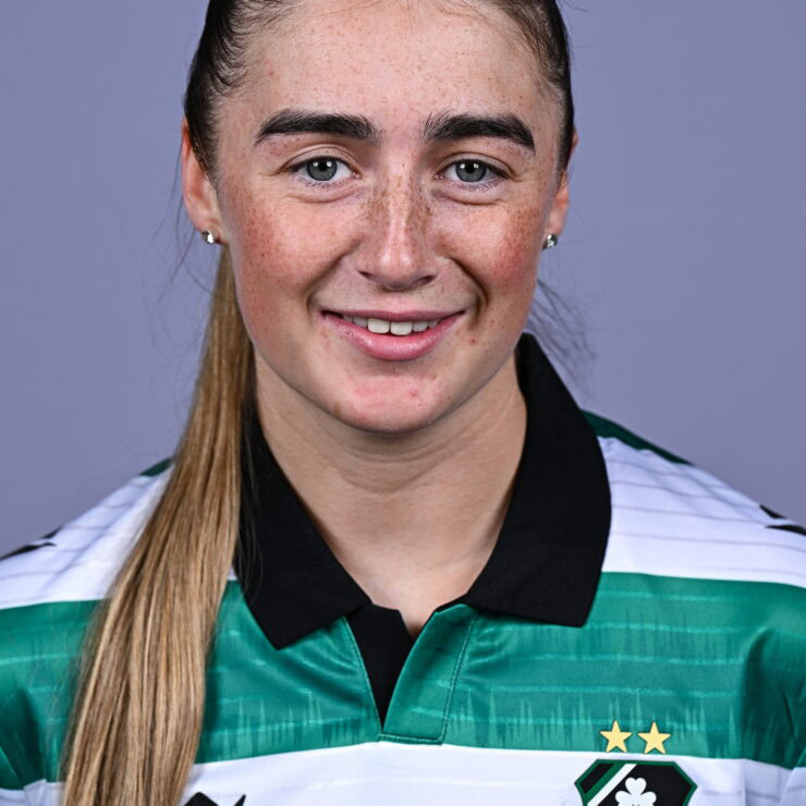 Female Shamrock Rovers player in team jersey smiling at camera.
