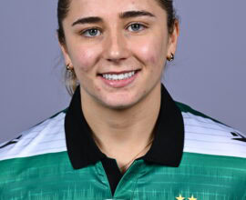 Female Shamrock Rovers player smiling in team jersey.