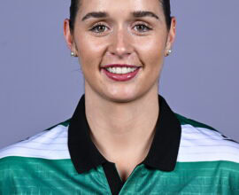 Female Shamrock Rovers player in team jersey smiling at camera.