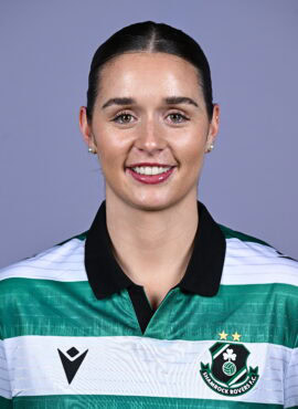 Female Shamrock Rovers player in team jersey smiling at camera.