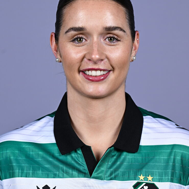 Female Shamrock Rovers player in team jersey smiling at camera.