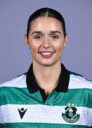 Female Shamrock Rovers player in team jersey smiling at camera.