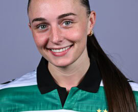 Female Shamrock Rovers player smiling in team jersey.