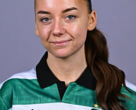 Female Shamrock Rovers player in team jersey, smiling confidently.