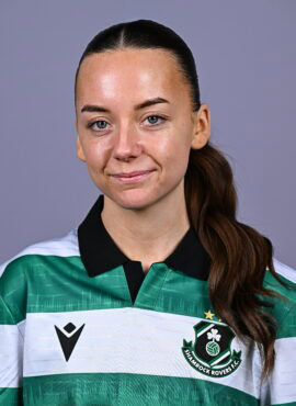 Female Shamrock Rovers player in team jersey, smiling confidently.