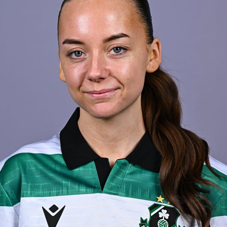 Female Shamrock Rovers player in team jersey, smiling confidently.
