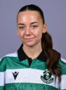 Female Shamrock Rovers player in team jersey, smiling confidently.