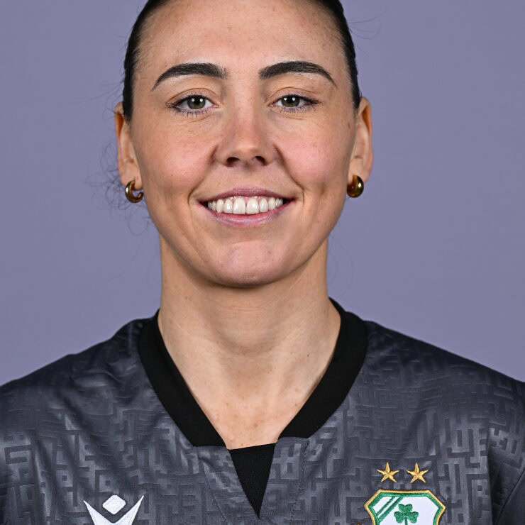 Female Shamrock Rovers player smiling in team jersey.