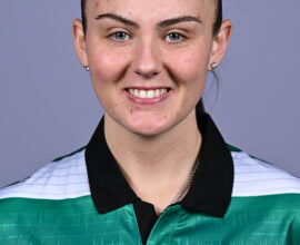 Female Shamrock Rovers player smiling in team jersey.