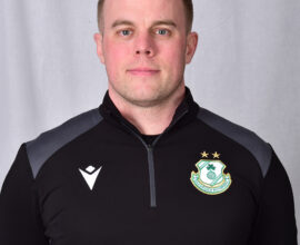 Shamrock Rovers player in team kit with club crest, facing forward.