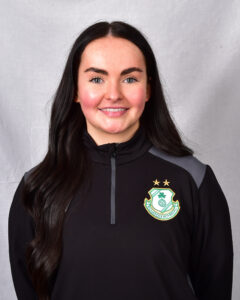 Female Shamrock Rovers player in team kit smiling at camera.
