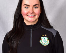 Female Shamrock Rovers player in team kit smiling at camera.