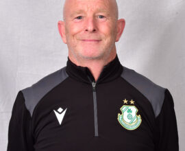 Shamrock Rovers coach in team gear, smiling, standing against a neutral background.