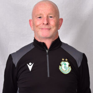 Shamrock Rovers coach in team gear, smiling, standing against a neutral background.